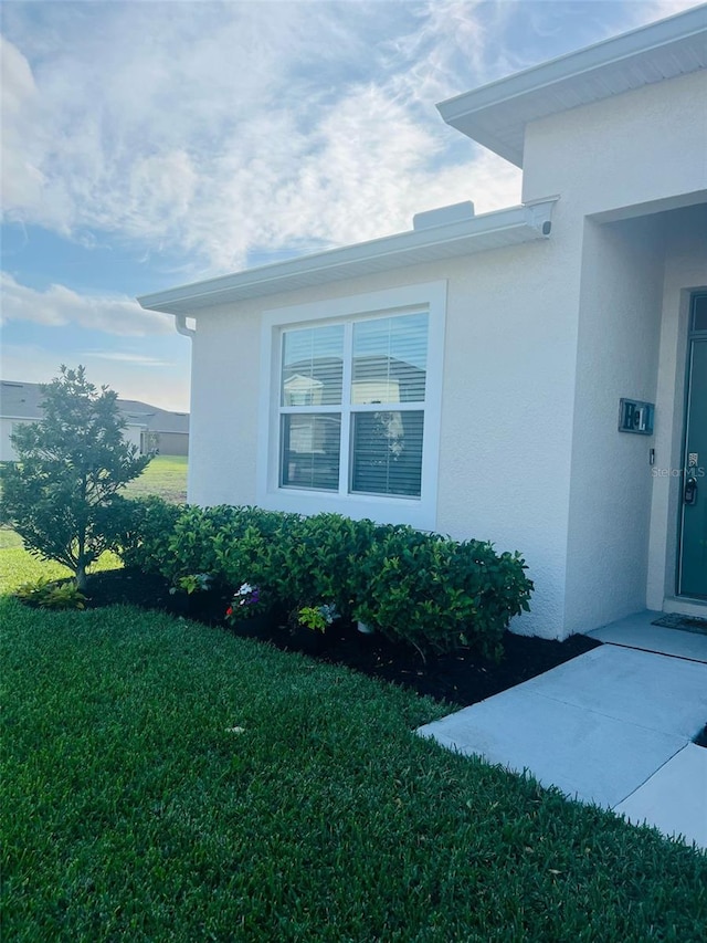 view of home's exterior with stucco siding and a yard