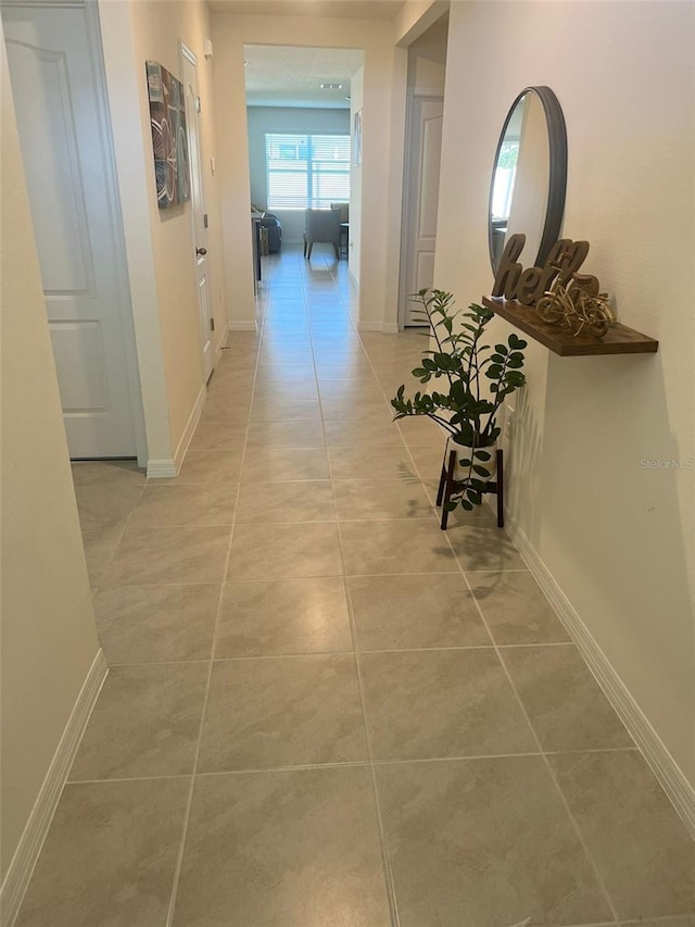 hall featuring light tile patterned floors and baseboards