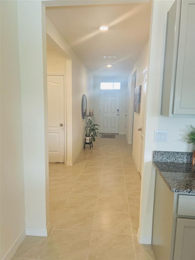 corridor with light tile patterned floors, baseboards, and recessed lighting