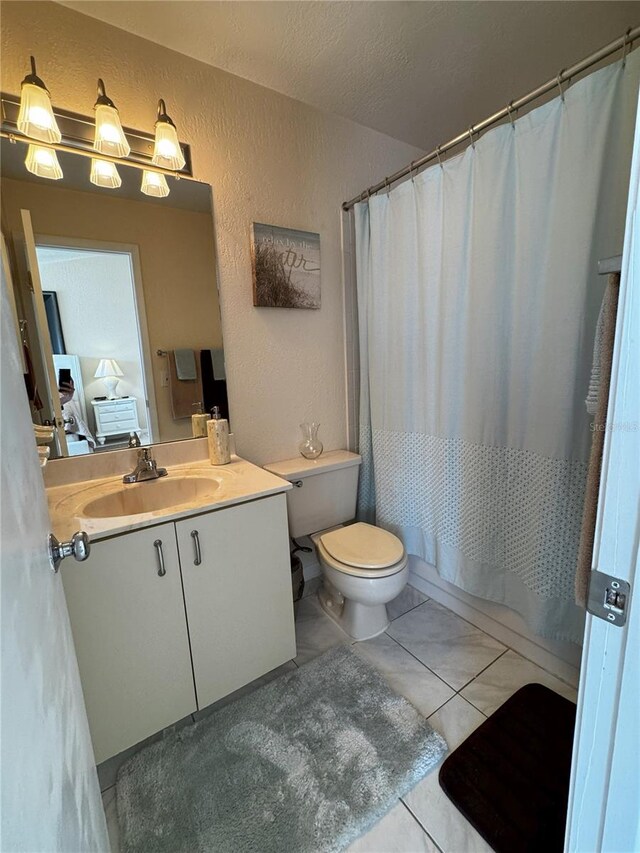 2520 Woodgate Blvd Unit 202, Orlando, FL 32822 - bathroom with a textured wall, toilet, vanity, tile patterned floors, and shower / tub combo with curtain