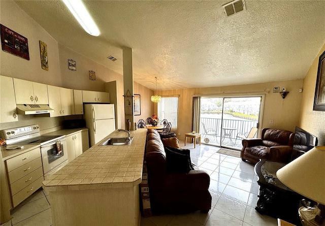 kitchen with sink, white refrigerator, a notable chandelier, tile counters, and stainless steel range with electric cooktop