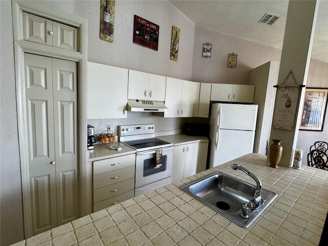 kitchen featuring sink, tile countertops, cream cabinets, vaulted ceiling, and white appliances