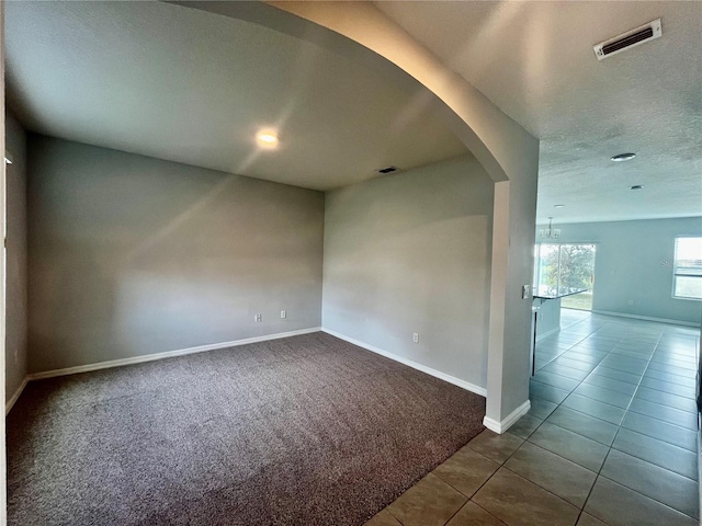 unfurnished room featuring carpet, a notable chandelier, and a textured ceiling