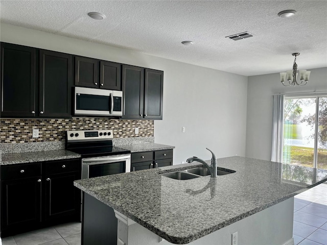 kitchen with light stone counters, sink, a center island with sink, and appliances with stainless steel finishes