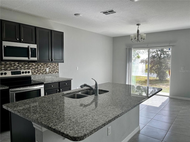 kitchen featuring light stone countertops, stainless steel appliances, a center island with sink, and sink