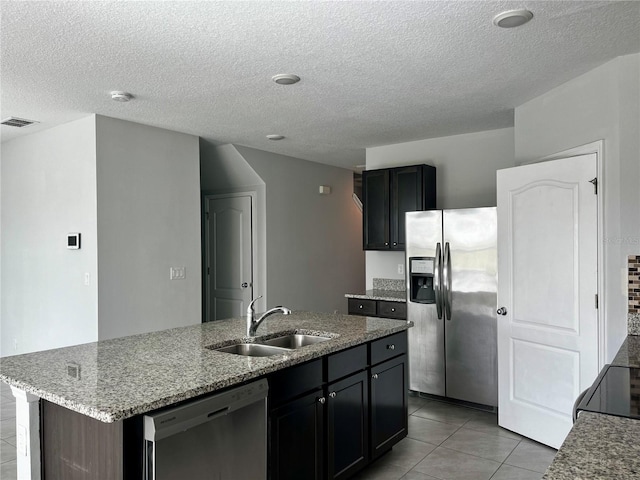 kitchen featuring a kitchen island with sink, sink, stainless steel appliances, and a textured ceiling