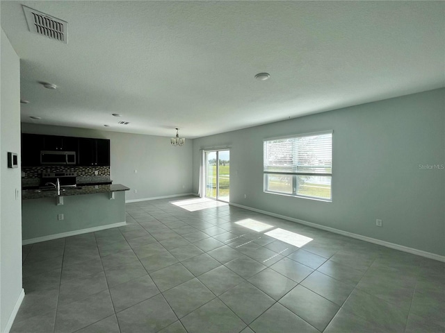 unfurnished living room with light tile patterned floors and an inviting chandelier