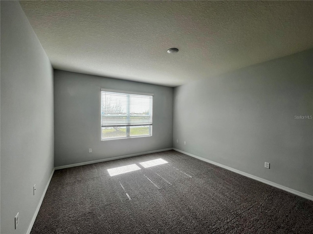 spare room with dark carpet and a textured ceiling