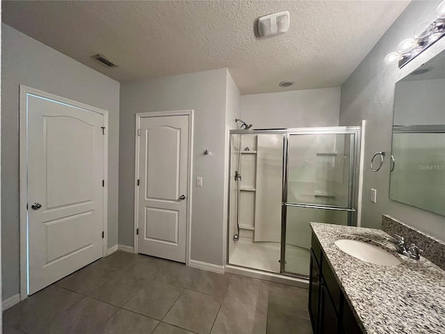 bathroom with tile patterned floors, vanity, an enclosed shower, and a textured ceiling