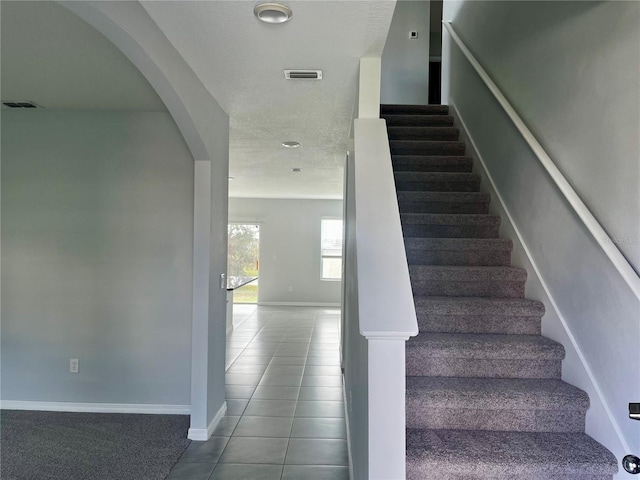 stairs with tile patterned flooring and a textured ceiling