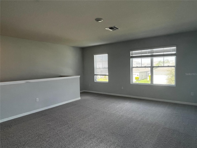 unfurnished room featuring dark carpet and a textured ceiling