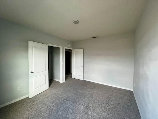 unfurnished bedroom with dark carpet and a closet