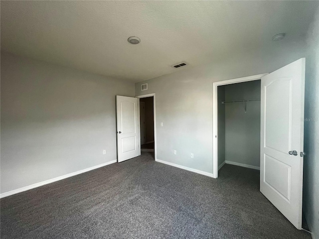 unfurnished bedroom featuring a closet, a textured ceiling, and dark colored carpet