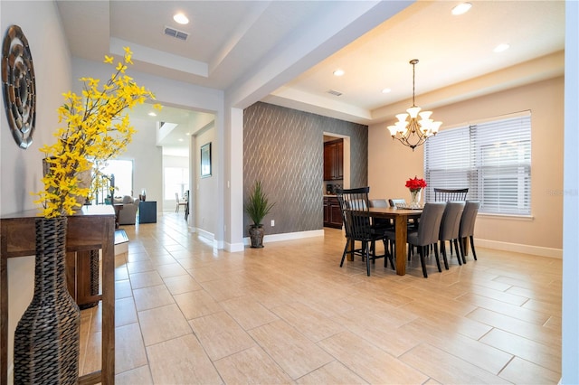 dining space with a tray ceiling, a wealth of natural light, and a notable chandelier