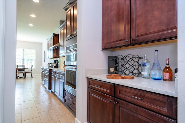 kitchen with light tile patterned floors, light stone counters, and double oven