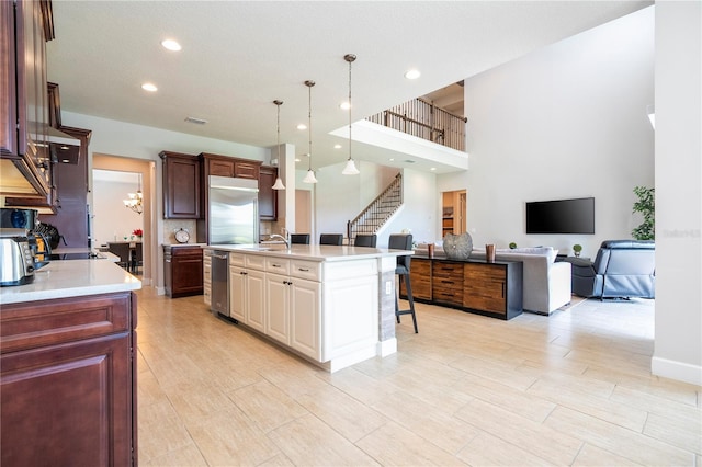 kitchen featuring sink, built in fridge, hanging light fixtures, a breakfast bar area, and an island with sink