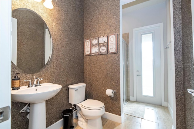 bathroom with tile patterned floors, toilet, a shower with shower door, and sink