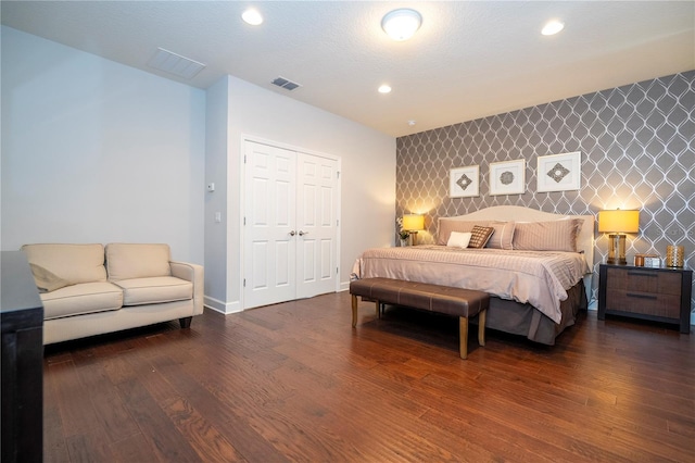 bedroom featuring a textured ceiling, dark wood-type flooring, and a closet