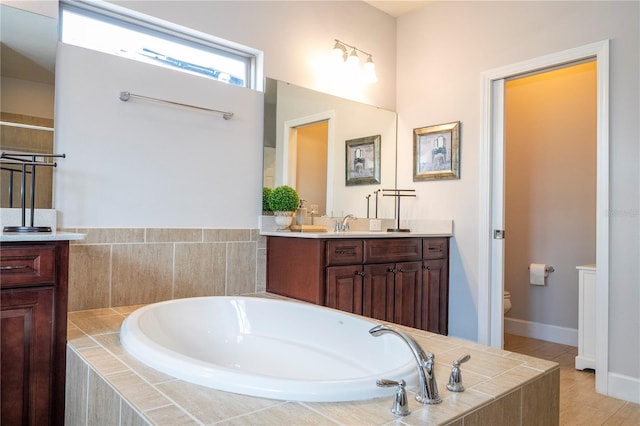 bathroom featuring tile patterned flooring, vanity, toilet, and tiled tub