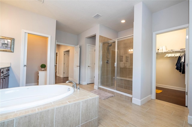 bathroom with wood-type flooring, vanity, shower with separate bathtub, and a textured ceiling