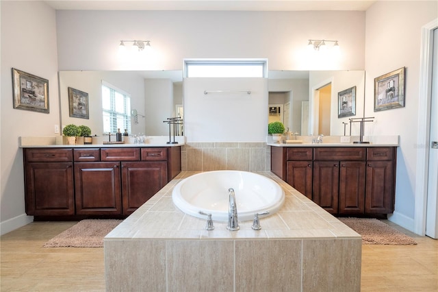 bathroom featuring tile patterned flooring, vanity, and a relaxing tiled tub