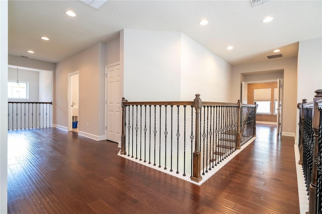 hall with a healthy amount of sunlight, dark hardwood / wood-style flooring, and a textured ceiling