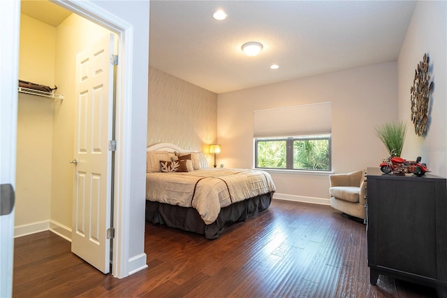 bedroom with a spacious closet, a closet, and dark hardwood / wood-style floors