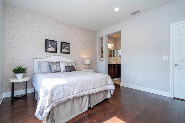 bedroom featuring connected bathroom and dark wood-type flooring