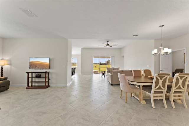 tiled dining room with ceiling fan with notable chandelier and a textured ceiling