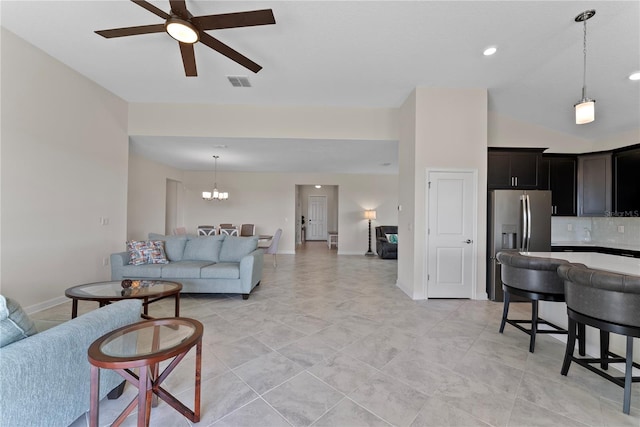 tiled living room featuring high vaulted ceiling and ceiling fan with notable chandelier