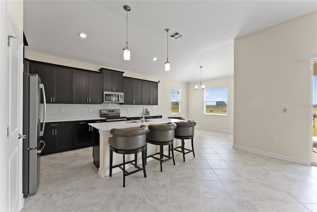 kitchen featuring pendant lighting, a breakfast bar, an island with sink, and appliances with stainless steel finishes