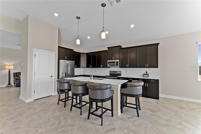 kitchen featuring a kitchen island with sink, sink, decorative light fixtures, dark brown cabinets, and stainless steel appliances