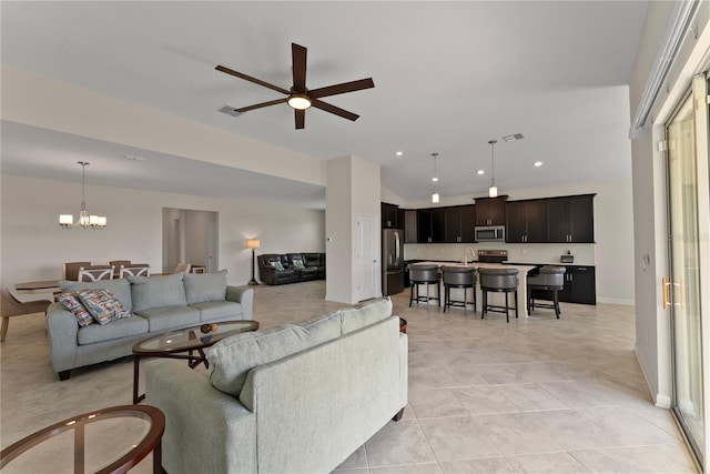 living room featuring ceiling fan with notable chandelier, light tile patterned flooring, and sink