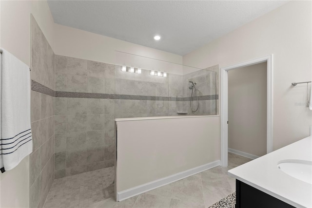 bathroom with tiled shower, a textured ceiling, vanity, and tile patterned floors