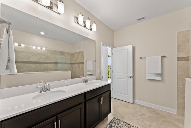 bathroom featuring tile patterned floors, vanity, a tile shower, and a textured ceiling