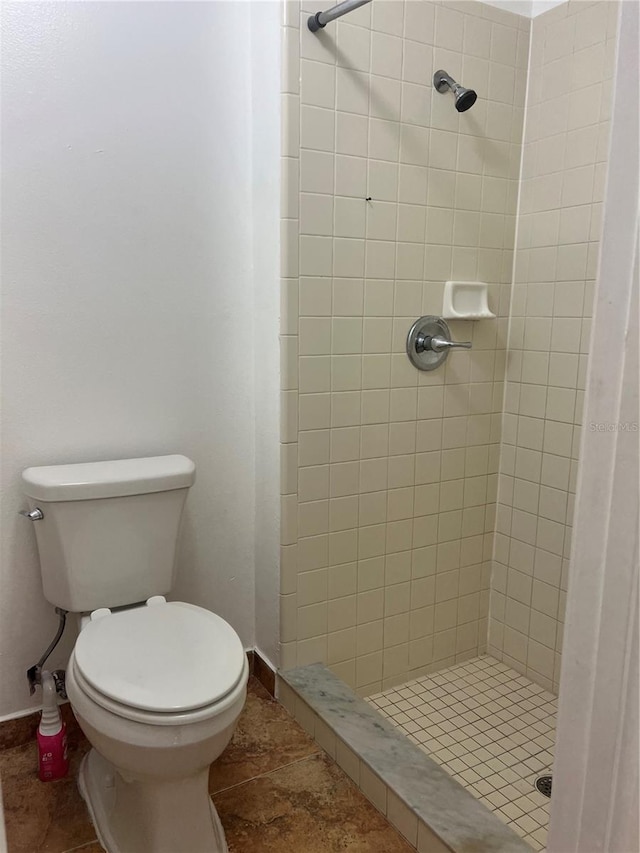 bathroom with tile patterned floors, toilet, and tiled shower