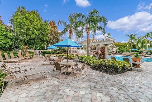 12843 Madison Pointe Cir Unit 107, Orlando, FL 32821 - view of patio featuring a community pool and a pergola