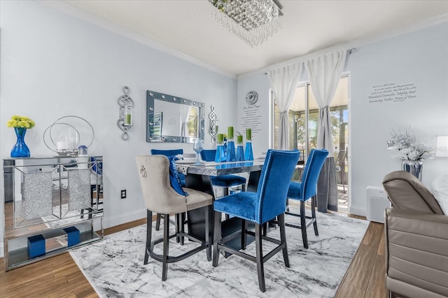 dining room with an inviting chandelier, wood-type flooring, and ornamental molding