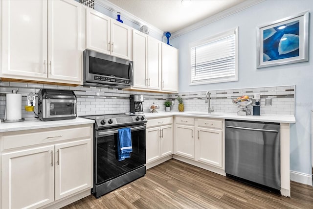 kitchen featuring appliances with stainless steel finishes, crown molding, sink, wood-type flooring, and white cabinetry