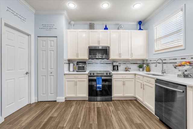 kitchen with sink, light hardwood / wood-style flooring, stainless steel appliances, and ornamental molding