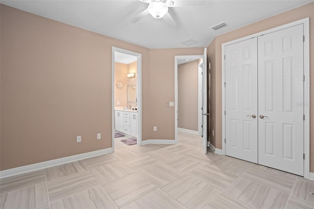 unfurnished bedroom with ceiling fan, ensuite bath, a closet, and sink