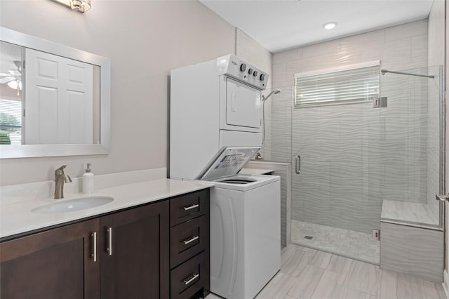 bathroom featuring ceiling fan, stacked washer and clothes dryer, a shower with shower door, and vanity