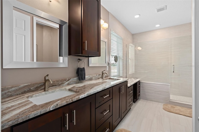 bathroom featuring a shower with shower door and vanity