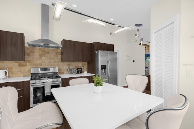 kitchen featuring a breakfast bar, a center island, backsplash, wall chimney range hood, and appliances with stainless steel finishes