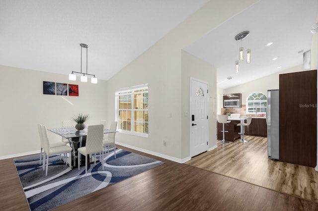 dining area featuring a healthy amount of sunlight, vaulted ceiling, and hardwood / wood-style flooring