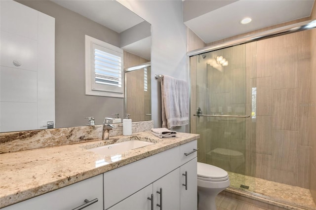 bathroom featuring an enclosed shower, vanity, and toilet