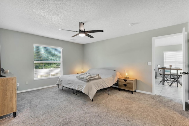 bedroom featuring ceiling fan, light colored carpet, and a textured ceiling