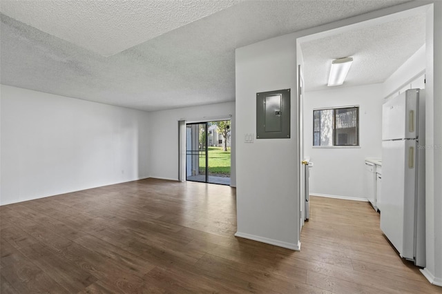 unfurnished room featuring a textured ceiling, electric panel, and light hardwood / wood-style flooring