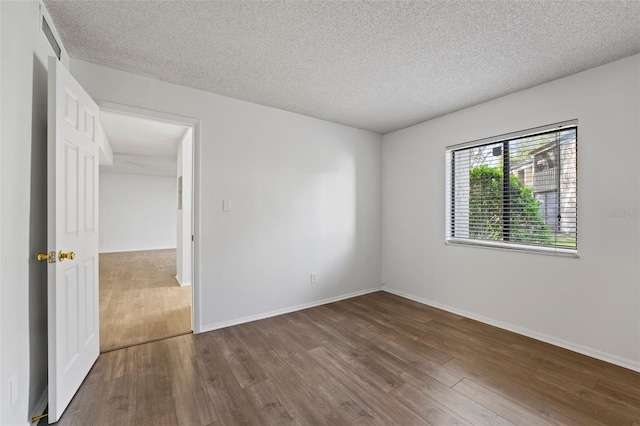 empty room with hardwood / wood-style flooring and a textured ceiling