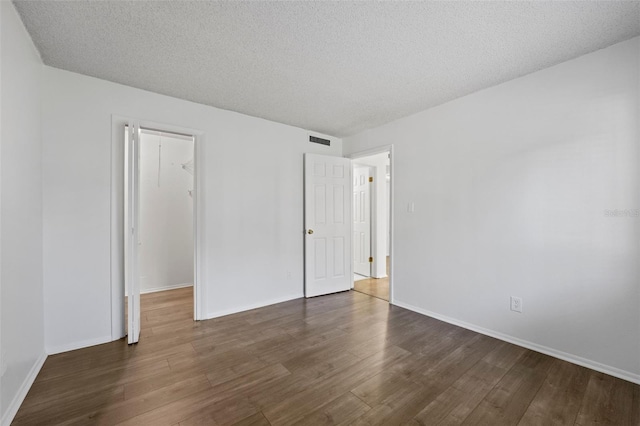 unfurnished room featuring a textured ceiling and dark hardwood / wood-style floors